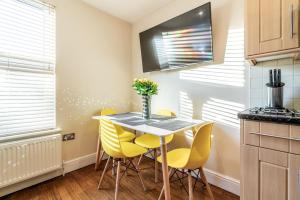 a kitchen with a table and yellow chairs at One Bedroom Flat in Bush Hill Park in Enfield