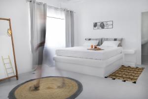 a white bedroom with a bed and a mirror at Vista Infinita in Agios Ioannis Mykonos