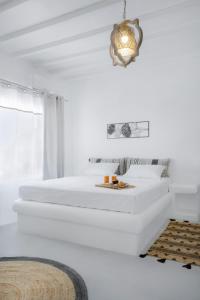 a white bedroom with two beds and a chandelier at Vista Infinita in Agios Ioannis Mykonos