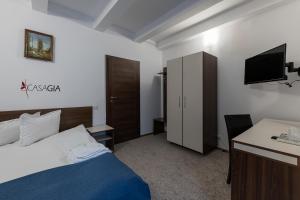 a bedroom with a bed and a desk and a television at Pension Casa Gia in Cluj-Napoca