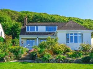 a white house with blue windows and a yard at Nicosia House with sea views. in Westward Ho