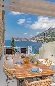 einen Holztisch und Stühle auf einer Terrasse mit Blick auf das Wasser in der Unterkunft St Jakov Superior Beach Apartment with Free Parking in Dubrovnik