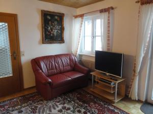 a living room with a leather chair and a television at Haus Fiedler in Piding