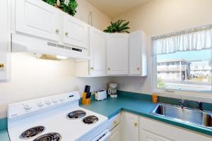 a kitchen with white cabinets and a sink and a stove at Captain's Deck in Ocean City