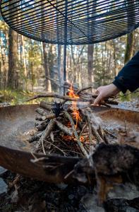 a person is cooking food over a fire at Domek z SAUNĄ na leśnej działce w Wildze in Wilga