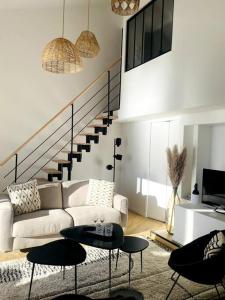 ein Wohnzimmer mit einem Sofa, Tischen und einer Treppe in der Unterkunft Magnifique duplex vue mer inoubliable Sanary Sur Mer in Sanary-sur-Mer