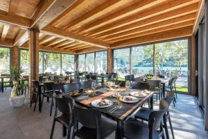 a dining room with tables and chairs and large windows at HOTEL TRILAGO in Trasaghis