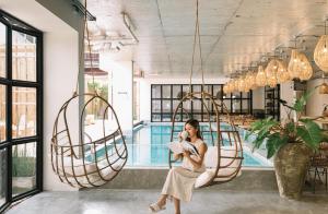 a woman sitting on a swing in front of a pool at Glory Wabi Sabi Hotel 清迈古城荣耀侘寂酒店 in Chiang Mai
