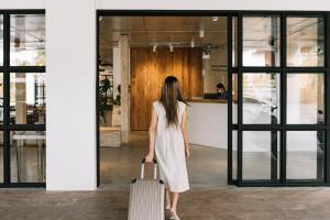 a woman walking through an office with a suitcase at Glory Wabi Sabi Hotel清迈古城荣耀侘寂酒店 in Chiang Mai