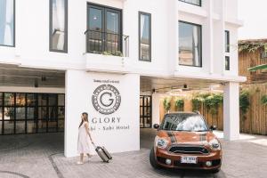 a woman standing in front of a car dealership at Glory Wabi Sabi Hotel 清迈古城荣耀侘寂酒店 in Chiang Mai