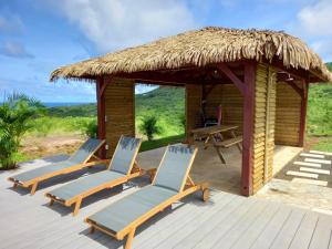 a deck with two chairs and a hut at Villa de 3 chambres avec vue sur la mer piscine privee et jacuzzi a Le Marin in Le Marin