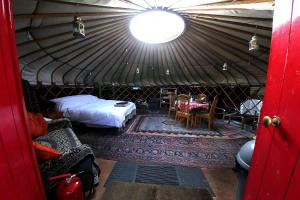 a room with a bed and a table in a yurt at Yurt luxury + Bathhouse in Callington