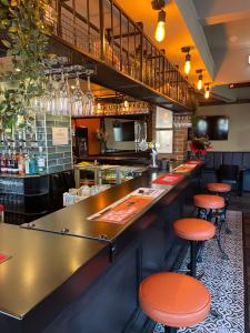 - un bar avec des tabourets orange dans un restaurant dans l'établissement Mersey view Hotel & Pub, à Hale