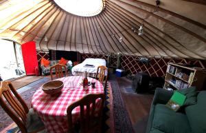 Yurt luxury + Bathhouse في Callington: غرفة مع طاولة وكراسي في يورت