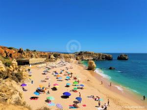 een groep mensen op een strand met parasols bij Apartamentos São Rafael - Albufeira, Algarve in Albufeira