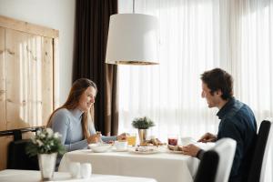 un hombre y una mujer sentados en una mesa comiendo comida en Lagació Hotel Mountain Residence, en San Cassiano