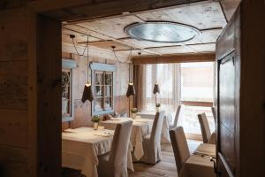 una sala da pranzo con tavoli e sedie bianchi di Lagació Hotel Mountain Residence a San Cassiano