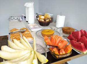 uma mesa coberta com pratos de frutas e produtos de pastelaria em Pousada Sol e Descanso em Arraial do Cabo