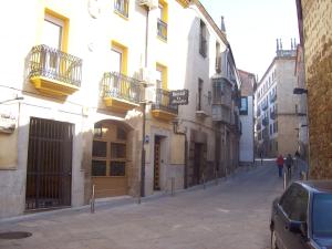 a city street with buildings and a car parked on the street at Hostal Muralla in Plasencia