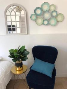 1 dormitorio con silla azul y espejo en Le Bahia centre la Brèche wifi linge de pressing, en Niort