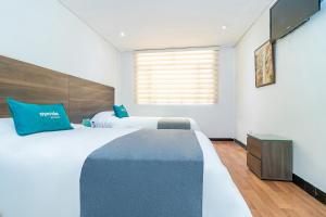 1 dormitorio con 2 camas con almohadas azules y ventana en Ayenda 1079 Bogotá Alpes Polo Club, en Bogotá