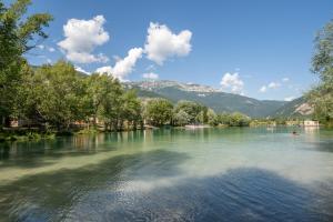 a view of a river with trees and mountains at Camping Le Lac Bleu in Châtillon-en-Diois