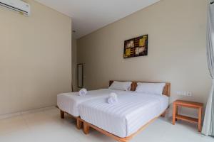 a bedroom with a white bed with two towels on it at Josh Guest House in Singaraja