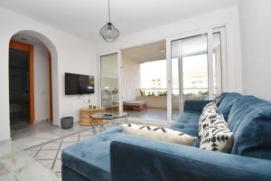 a living room with a blue couch and a tv at Expoholidays - Apartamentos Puerto Almerimar in Almerimar