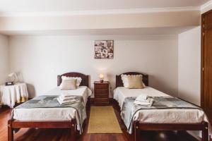 フンシャルにあるFunchal Downtown by ALMA Holiday Rentalsの白い壁とウッドフロアの客室で、ベッド2台が備わります。