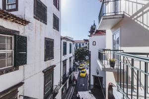 an alley between two buildings with a yellow car on the street at Funchal Downtown by ALMA Holiday Rentals in Funchal