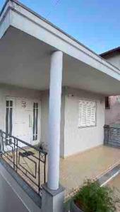 a white house with a porch and a white pole at Casa em bairro nobre, bem localizada, com suite. in Bento Gonçalves