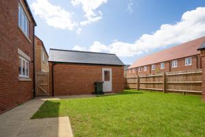a courtyard between two brick buildings with a fence at Immaculate 4-Bed House 5mins walk to Village shop in Bicester