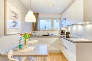 诺德奈AchterHuus的厨房配有白色橱柜和鲜花桌