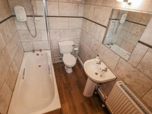 Un baño con bañera, inodoro y lavabo. en 2 The Old Coach House, en Ambleside