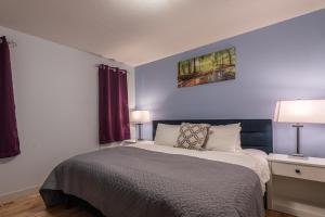 a bedroom with a bed and two tables and two lamps at Private Hot Tub - Private Front Yard with Mountain View Patio in Canmore
