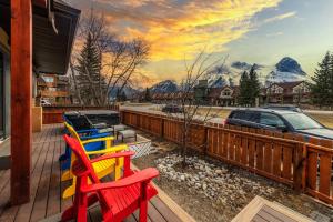 a row of colorful chairs on a deck with a mountain mural at Private Hot Tub / Yard /Patio - A/C- Mountain View Vacation Home in Canmore