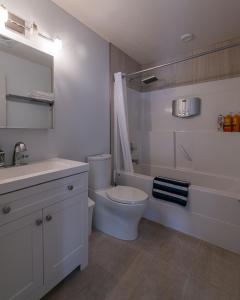 a white bathroom with a toilet and a sink at Private Hot Tub - Private Front Yard with Mountain View Patio in Canmore