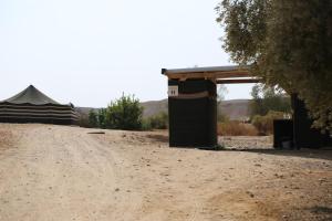 a dirt road next to a building and a tent at Desert Days mud cabin's Resort in Zuqim