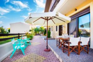 a patio with tables and chairs and an umbrella at Ekavi Villa in Skala Potamias