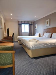 um quarto de hotel com duas camas e uma cadeira em Kegworth Hotel & Conference Centre em Castle Donington