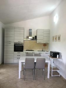 una cucina con tavolo e sedie bianchi di Casa Teresa a Porto Pino a Porto Pino