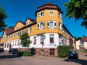 een groot geel en wit gebouw met auto's geparkeerd op straat bij Gasthof zur Krone in Bad König