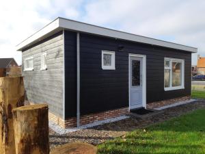 a black and grey tiny house with a door at Recreatiewoning Den Hollander in Aagtekerke