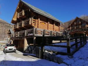 a log cabin in the snow with a car parked in front at Chalet Les Pins Blancs in Allos