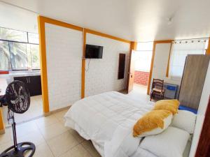 Schlafzimmer mit einem weißen Bett und einem Ventilator in der Unterkunft Los Faroles in Pacasmayo