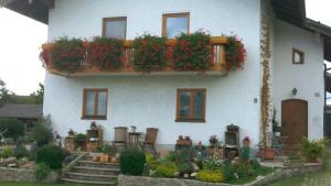 ein weißes Haus mit einem Balkon mit Pflanzen darauf in der Unterkunft Ferienwohnung Walter Gluche in Pittenhart