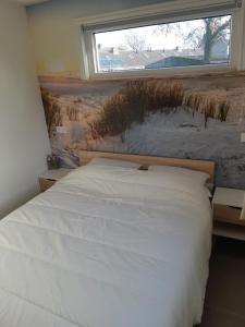 a bedroom with a white bed and a window at Recreatiewoning Den Hollander in Aagtekerke