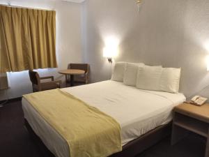 a hotel room with a bed, desk, and nightstand at EZ 8 Motel San Jose I in San Jose