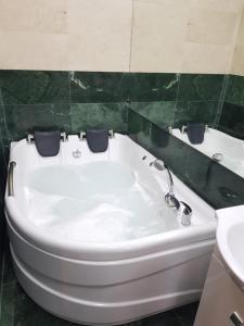 La salle de bains est pourvue d'une baignoire blanche et d'un mur vert. dans l'établissement Spa Mega Mall Monza National Arena, à Bucarest