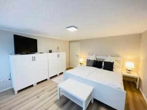 a bedroom with a white bed and a flat screen tv at Pension Mitte in Oldenburg